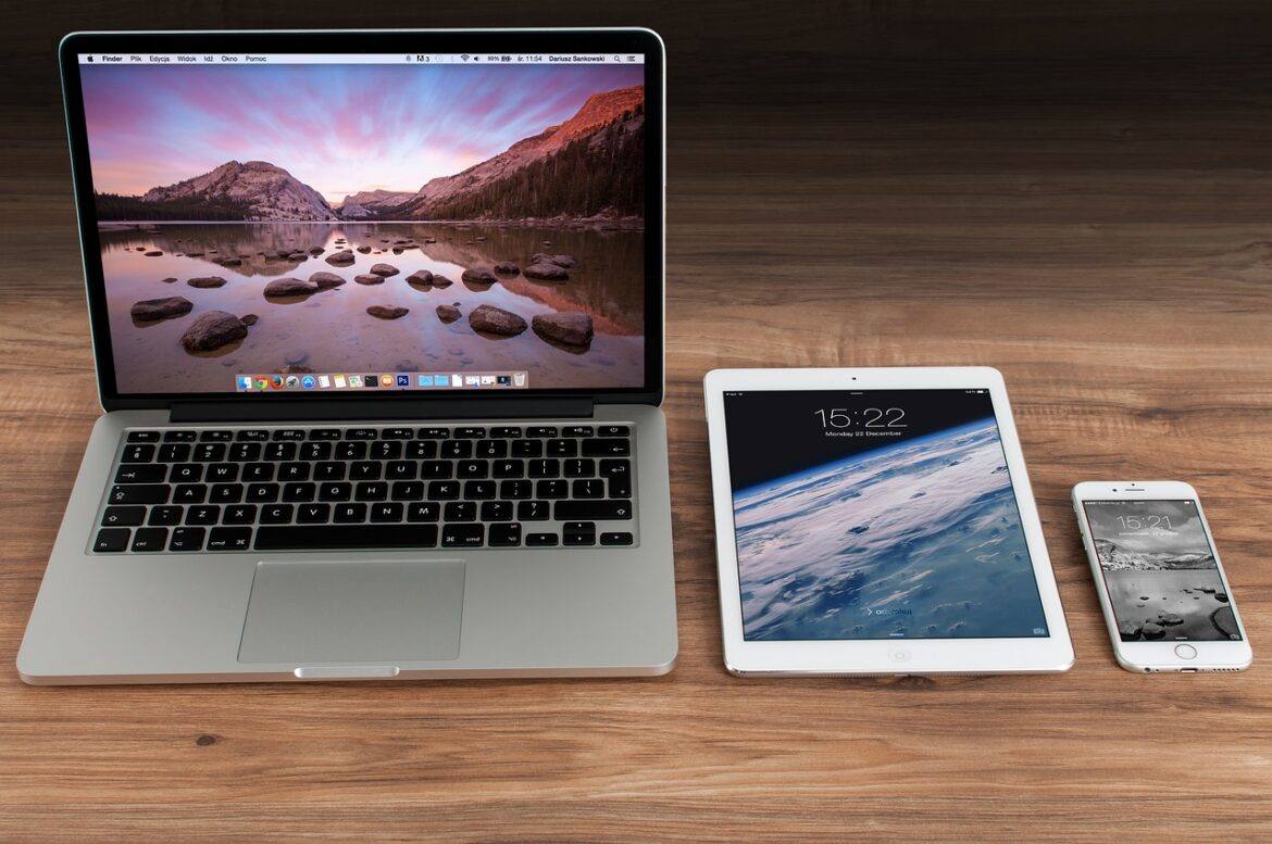 apple Image of a Macbook, iPad, and iPhone on a desk.