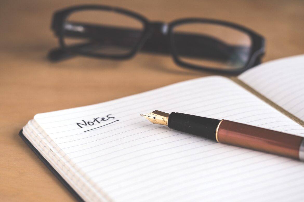 david-travis-5bYxXawHOQg-unsplash Notebook, pen, and glasses on a table