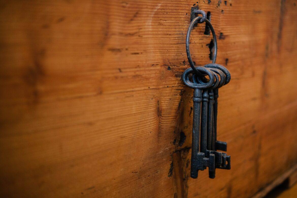 silas-kohler-C1P4wHhQbjM-unsplash old skeleton keys on a ring hanging from a hook in wood board
