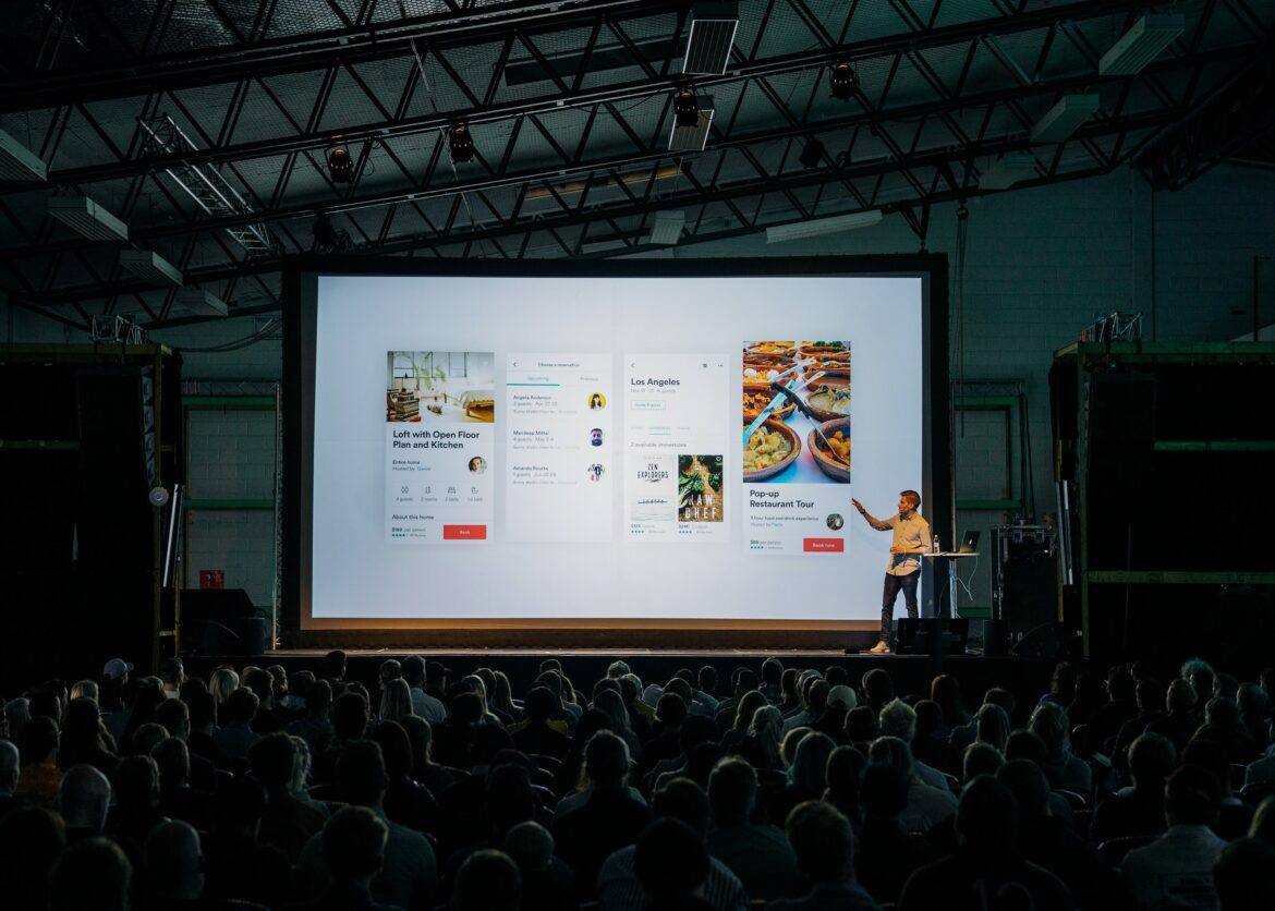 teemu-paananen-bzdhc5b3Bxs-unsplash Man speaking to large audience