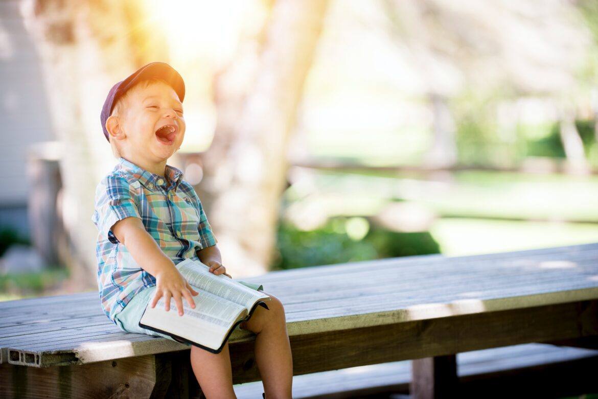 ben-white-4K2lIP0zc_k-unsplash repeated reading - child reading a book and laughing