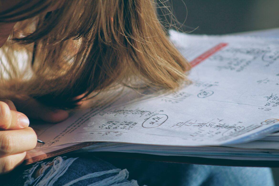joshua-hoehne-AZrBFoXP_3I-unsplash female working on math problem in notebook