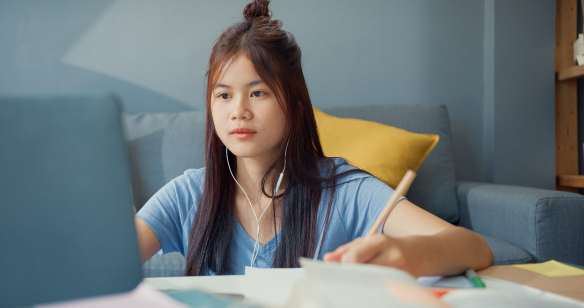 Young Asia girl teenager with casual wear headphones use laptop