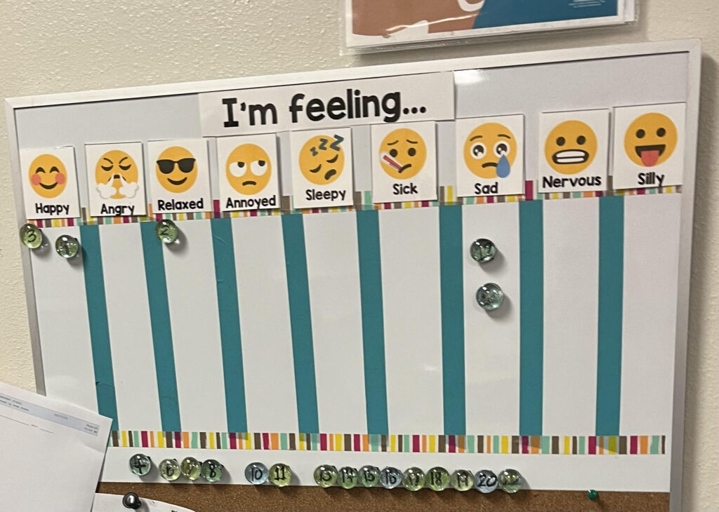 Image of a magnetic board with emoji choices for students to identify feelings