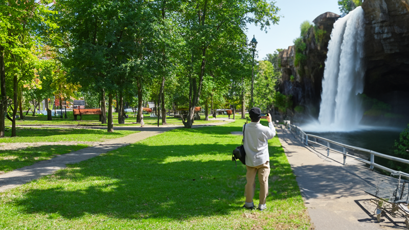 A photograph of a person taking a photo of a waterfall.