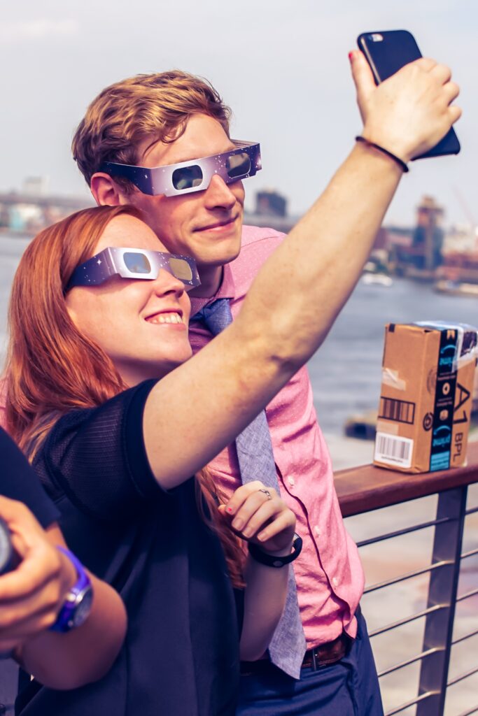 Two people posing for a selfie while wearing eclipse glasses